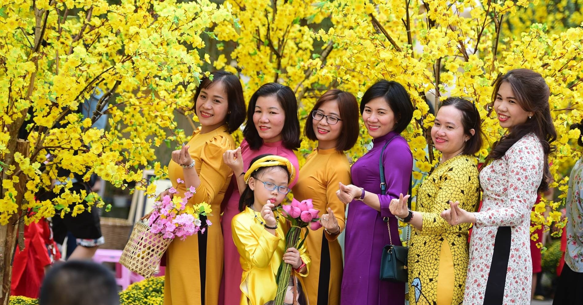 Hội chị em phụ nữ mặc áo dài truyền thống chụp hình với hoa mai Tết