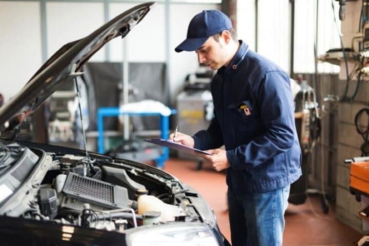 Nhân viên đánh giá kiểm tra động cơ để đăng kiểm ô tô